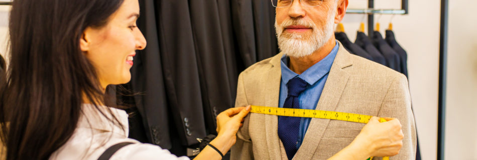 a professional tailor woman trying on a tailor-made suit for an elderly man